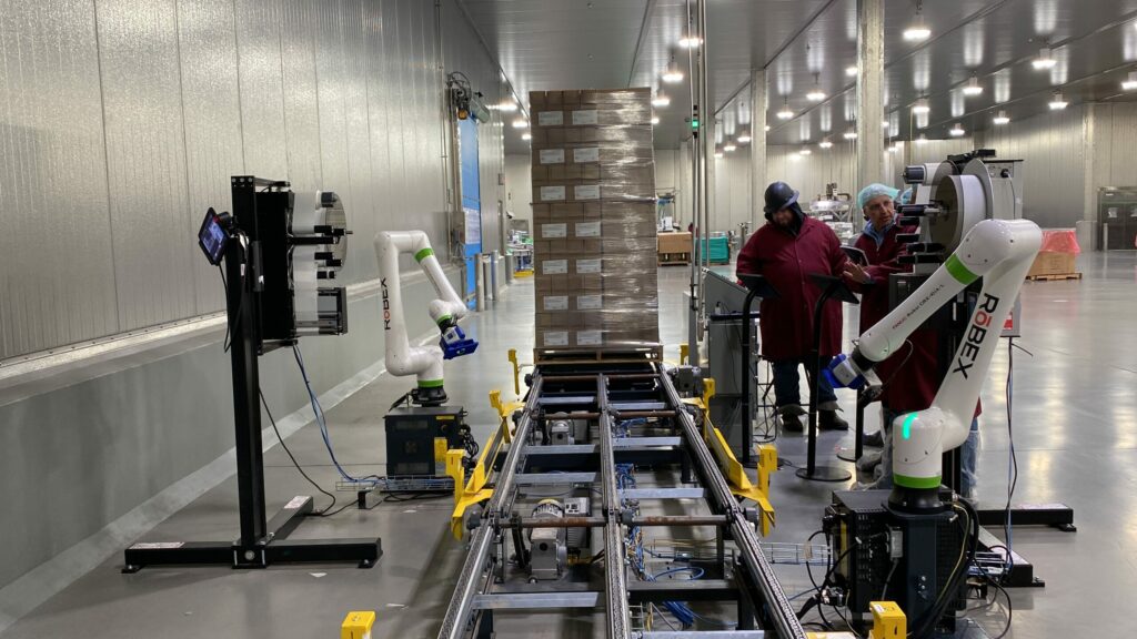 Two FANUC CRX collaborative robots waiting for a pallet to apply labels