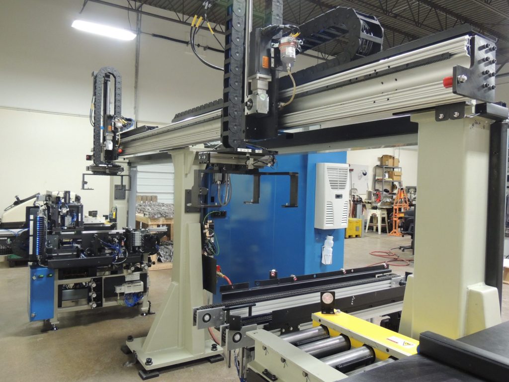 An industrial gantry system works to transfer parts in an assembly line.