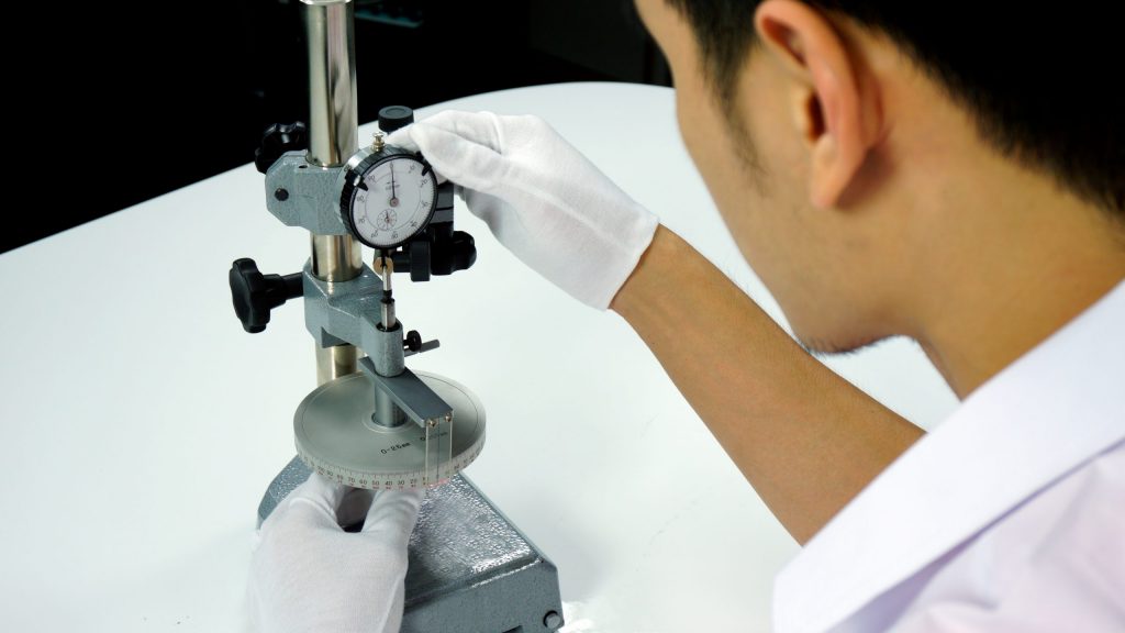 A metrology technician measures a part by hand on a micrometer