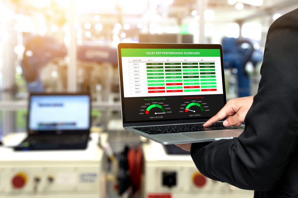 Factory manager in front of a machine using a laptop to do real-time monitoring.