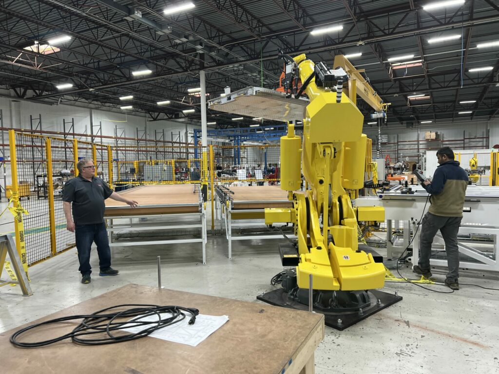 Employee programming a robot with enhanced robot safety standards in factory