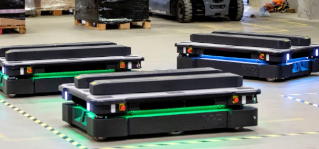Three black MiR autonomous mobile robots on a concrete floor.