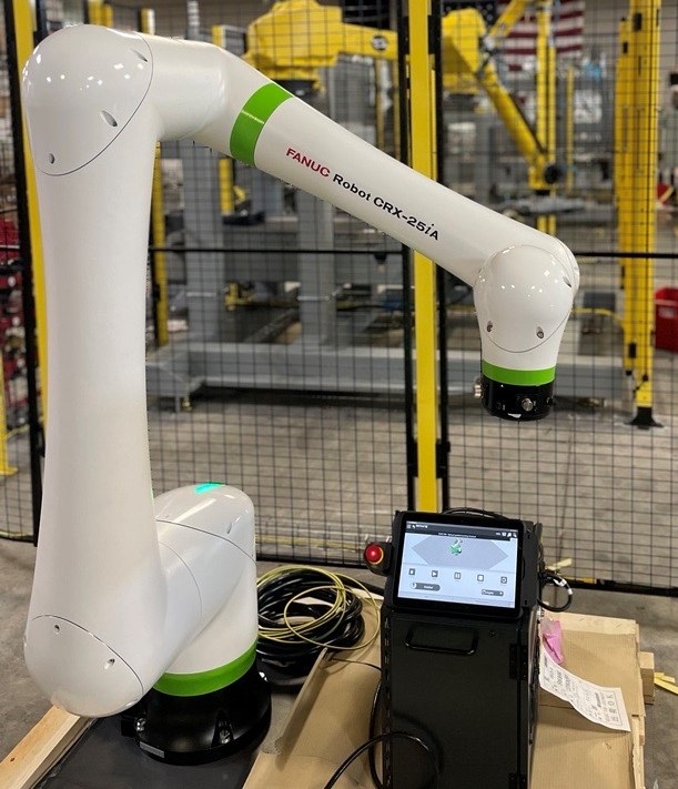 FANUC’s CRX collaborative robot is next to a small electronic device.