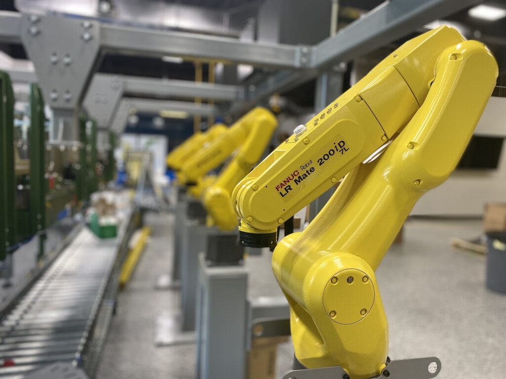 A photo of a row of yellow FANUC industrial robot arms.