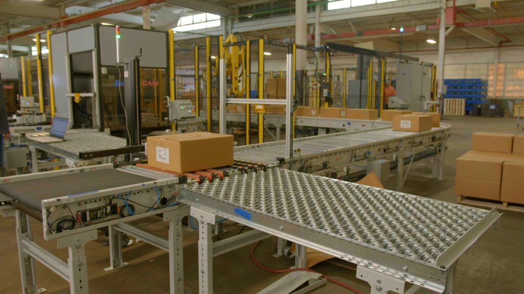 Cardboard boxes with virtual barcodes on them are being scanned on a conveyor belt.